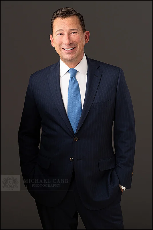 Personal Branding Photographer Businessman in a navy suit smiling during a modern Houston headshot session.