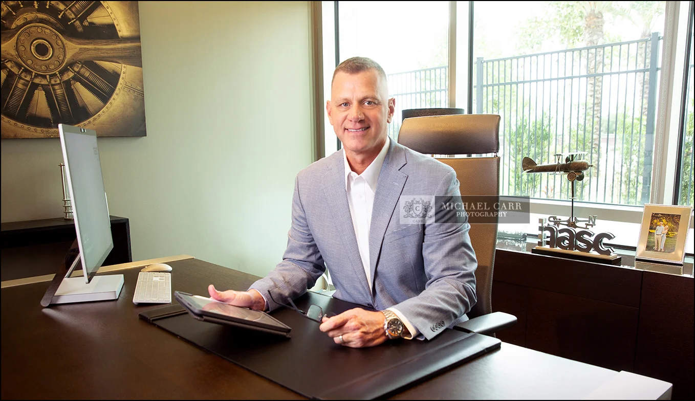 Executive branding portrait of a CEO seated at his office desk in Houston.