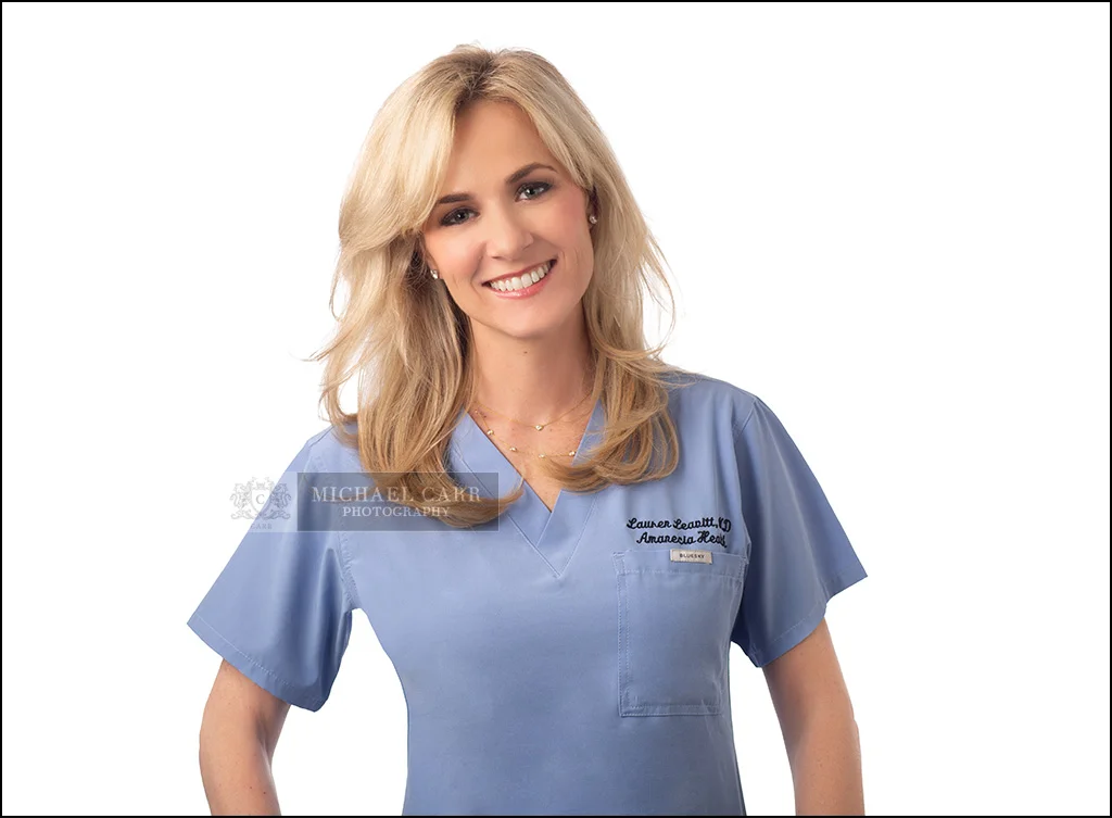 Smiling physician in blue scrubs photographed for a professional personal branding portrait.