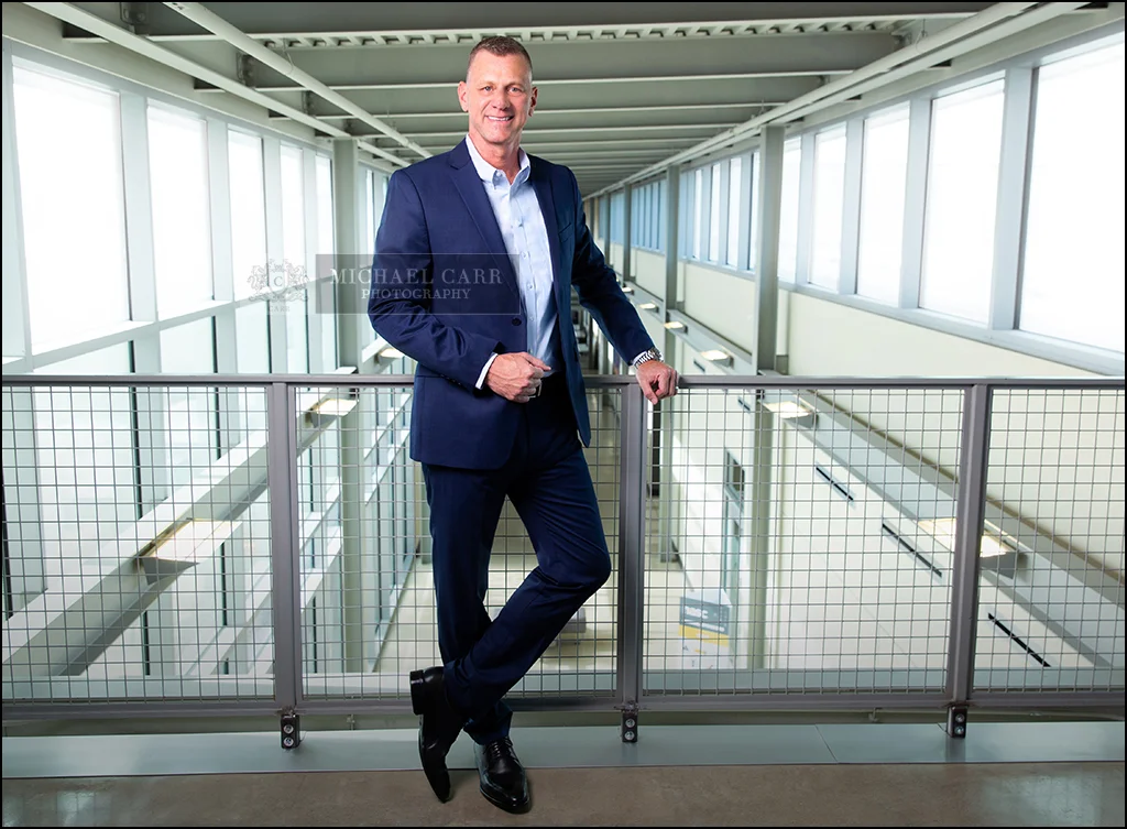 Personal branding portrait of a Houston CEO standing in a modern office corridor.