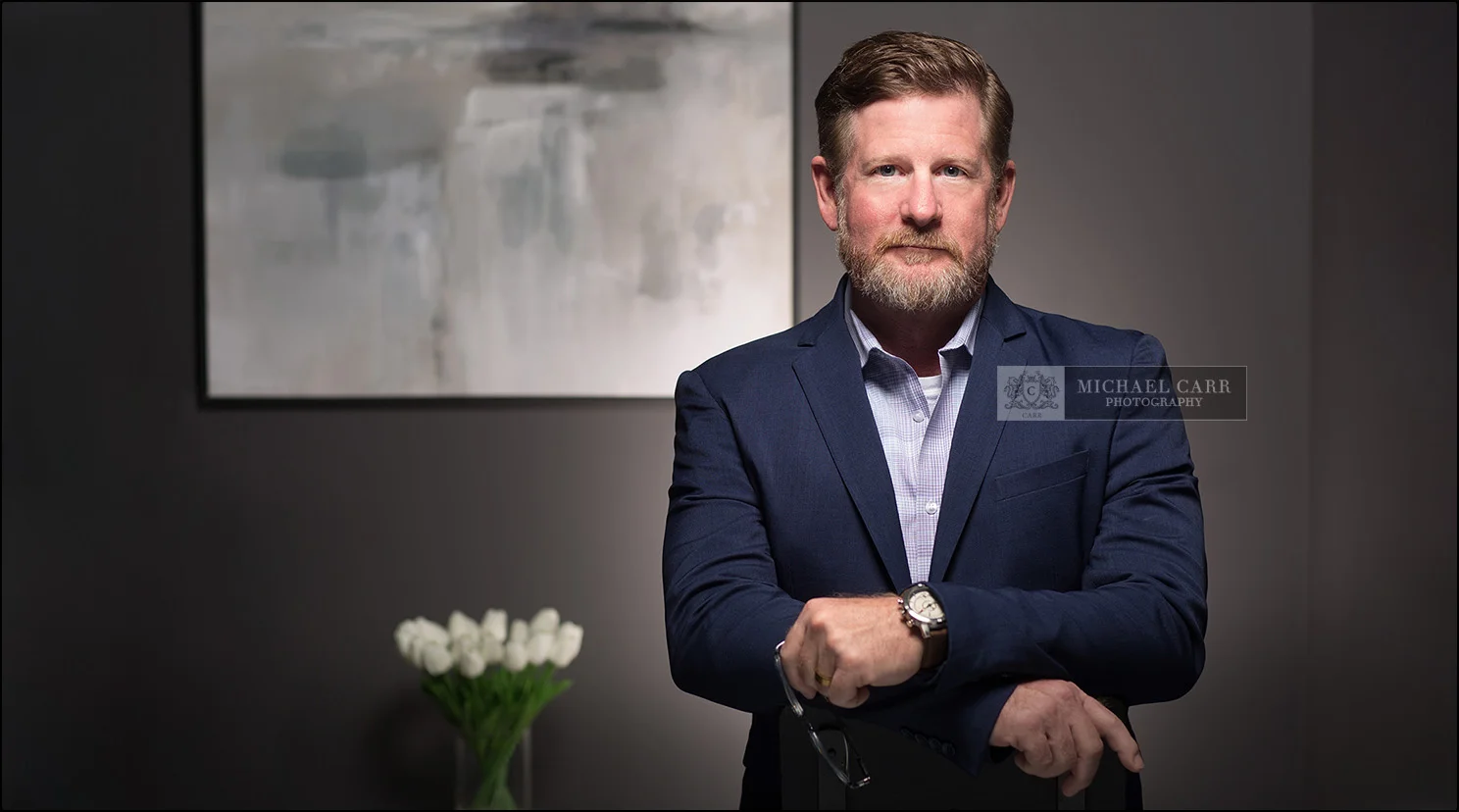 Executive branding portrait of a Houston businessman wearing a navy blazer in a modern office.
