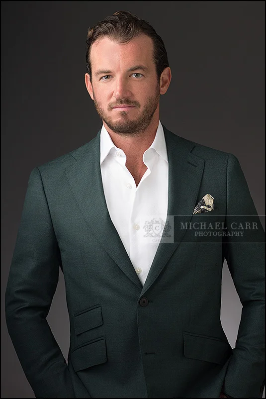 Personal Branding Photographer Executive portrait of a businessman wearing a green suit against a gray studio background.