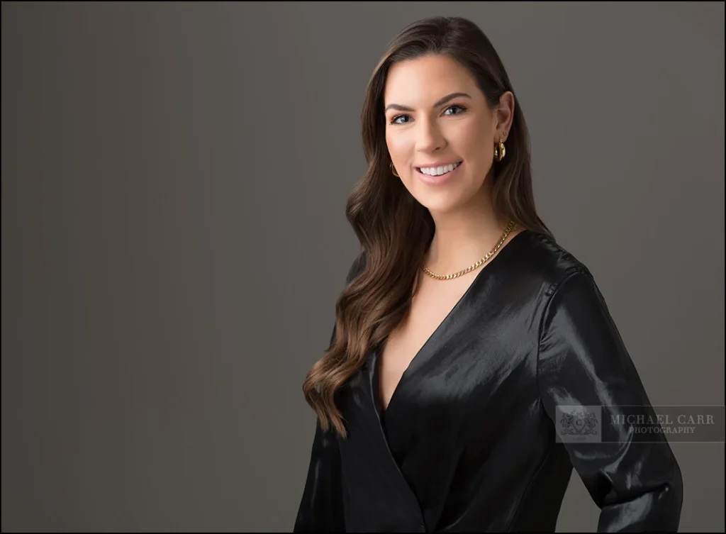 Professional branding portrait of a Houston businesswoman wearing a black blouse against a gray background.