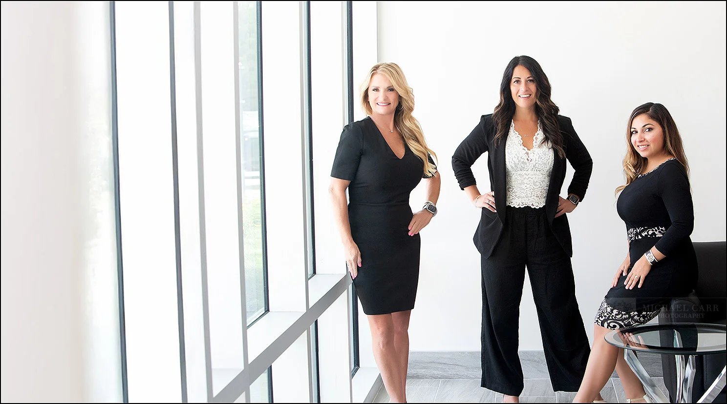 Three Houston businesswomen during a personal branding photography session in a modern office with natural window light.