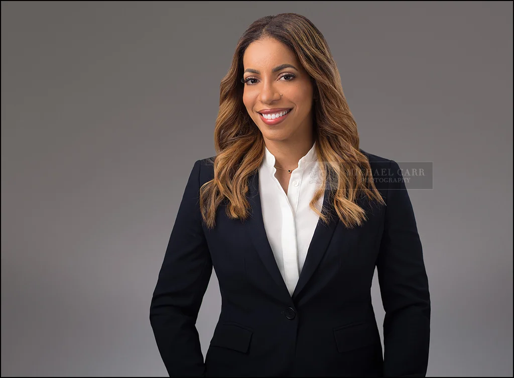 Personal Branding Photographer Smiling businesswoman in a navy blazer photographed on a soft gray studio background.