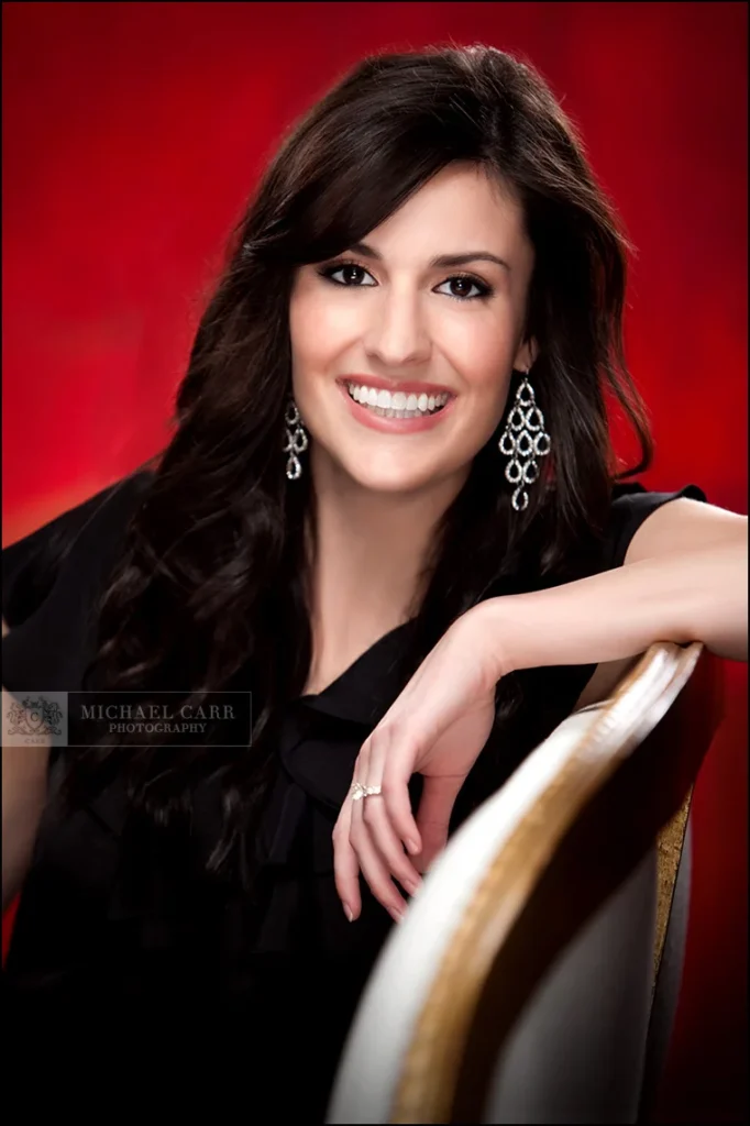 Personal Branding Photographer Smiling businesswoman photographed against a vibrant red studio background during a Houston headshot session.