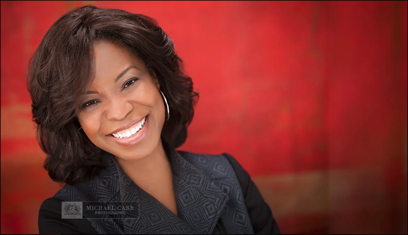 smiling-businesswoman-red-background Warm portrait of a smiling businesswoman photographed on a vibrant red studio backdrop.